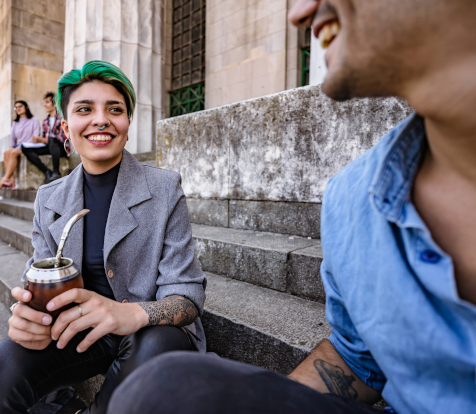 Two people sat on steps having a drink